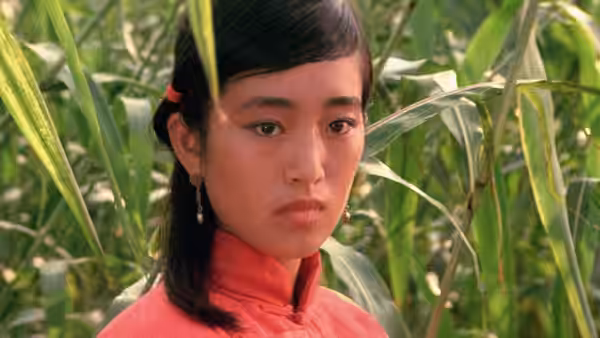 Jiu'er (Gong Li) stands among tall sorghum stalks in a red blouse