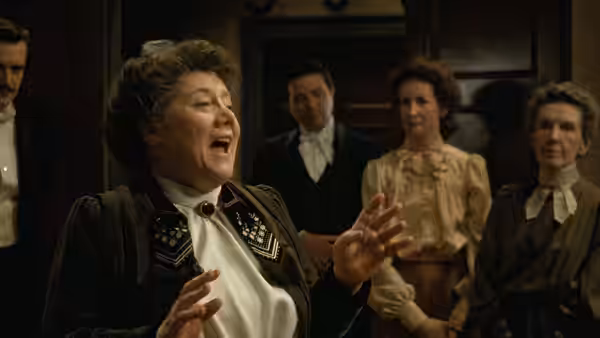 A woman sings to gathered guests in a warmly lit drawing room