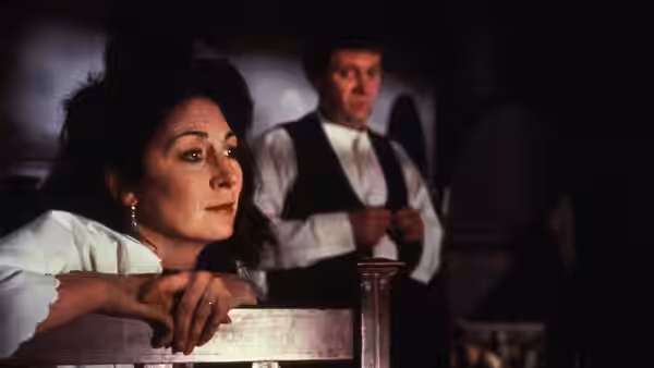 Gretta Conroy (Anjelica Huston) leans over a chair as a man stands behind her