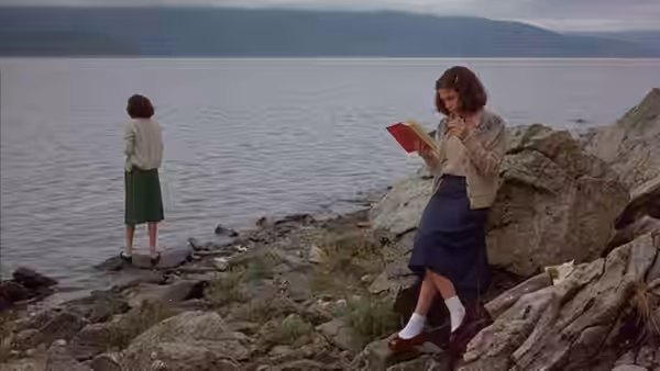 Ruth stands by the lakeshore as Sylvie Fisher (Christine Lahti) reads on the rocks