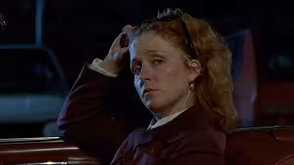 Irmeli Pihlaja (Susanna Haavisto) rests a hand on her head beside a car