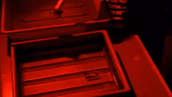 A red-lit metal compartment sits open, with a small object on its tray