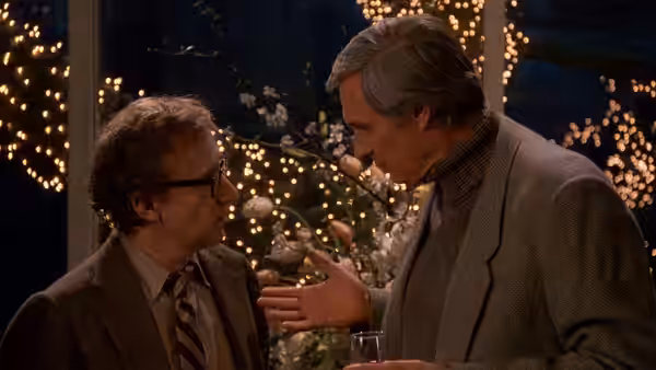 Cliff Stern (Woody Allen) listens as Lester (Alan Alda) gestures at a decorated gathering