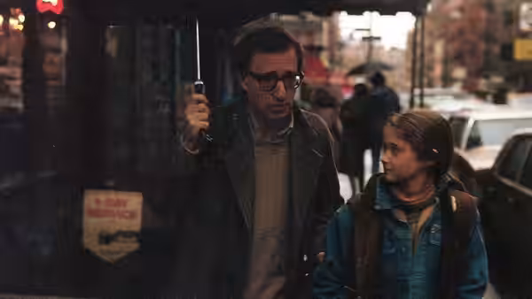Cliff Stern (Woody Allen) walks under an umbrella beside a young woman on a city street