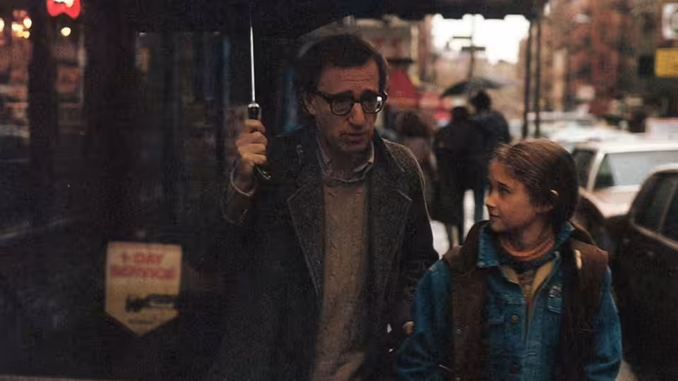 Cliff Stern (Woody Allen) walks under an umbrella beside a young woman on a city street