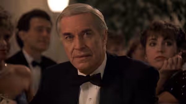 Judah Rosenthal (Martin Landau) sits in a tuxedo among guests at a formal gathering