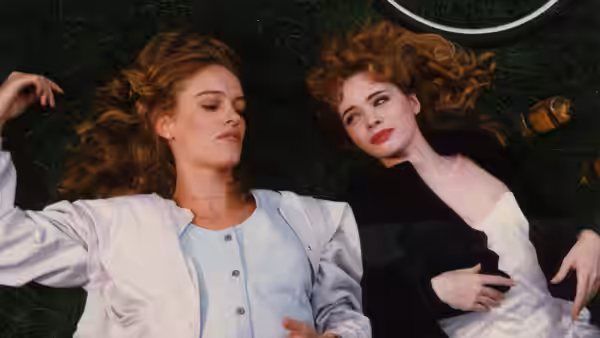 Two young women lie on the grass, one gazing upward