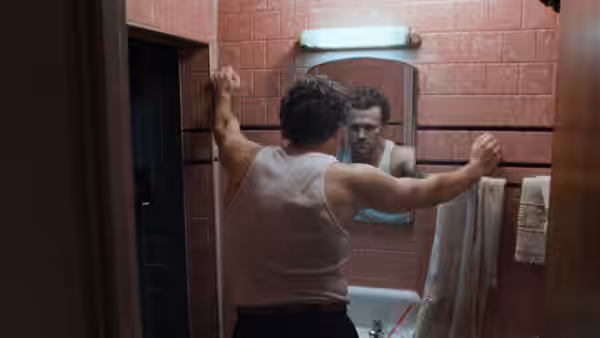Henry (Michael Rooker) braces himself against a bathroom wall, studying his reflection in the mirror