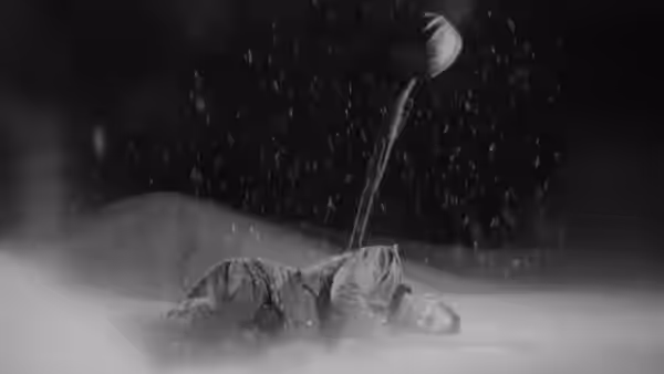 A person lies face down in the snow beside a shovel