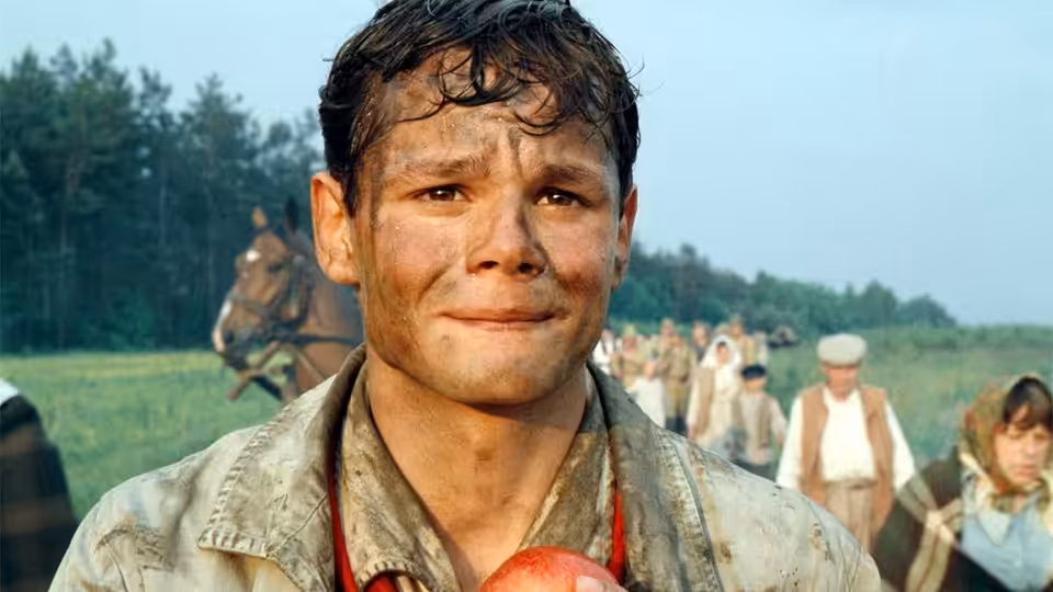 Salomon Perel (Marco Hofschneider) stands among laborers, holding an apple