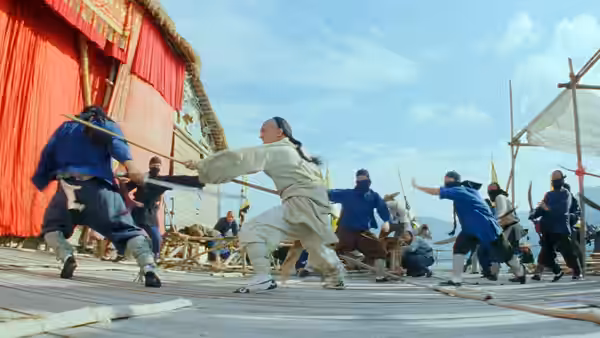 Wong Fei Hung (Jet Li) fights blue-clad attackers on a wooden platform