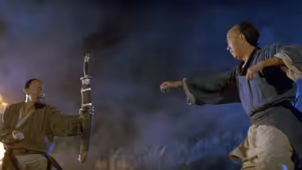 Two martial artists face off at night, one holding a sword