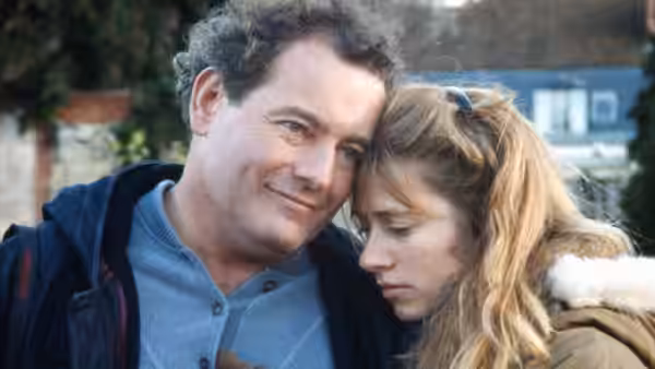Charles rests his head against Félicie as she looks down outdoors