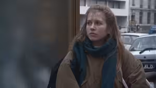 Félicie stands beside a doorway on a city street