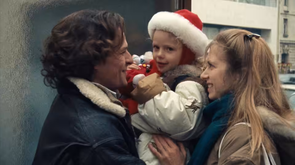 Charles and Félicie hold their young daughter between them on a city street