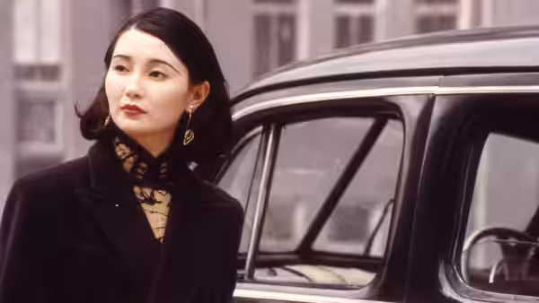 Ruan Lingyu (Maggie Cheung) stands beside a car, looking offscreen