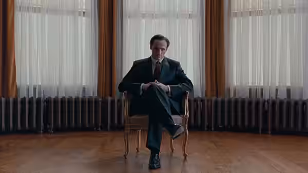 Glenn Gould (Colm Feore) sits with crossed legs in a chair before tall windows