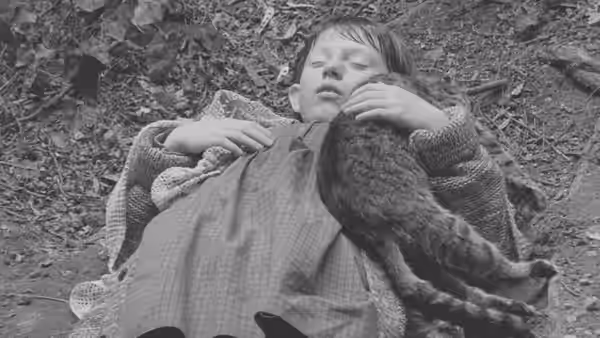 Estike (Erika Bók) lies on the ground holding a cat