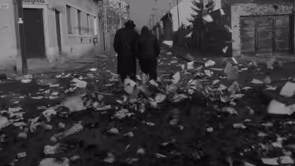 Two men walk through a litter-strewn village street