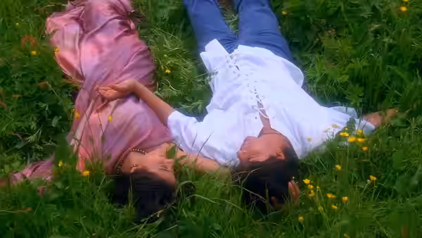 Raj Malhotra and Simran Singh lie side by side in a flower-dotted meadow