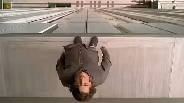 César (Eduardo Noriega) hangs upside down over a rooftop ledge