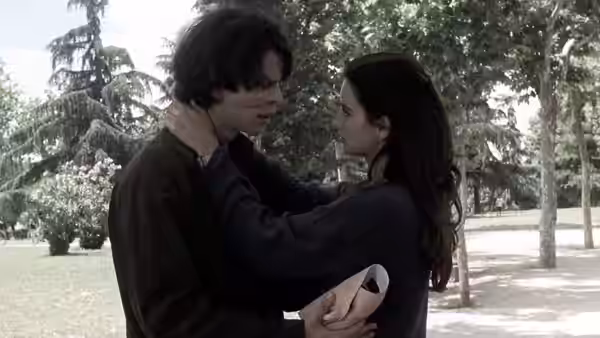 Sofía holds César by the neck in a tree-lined park