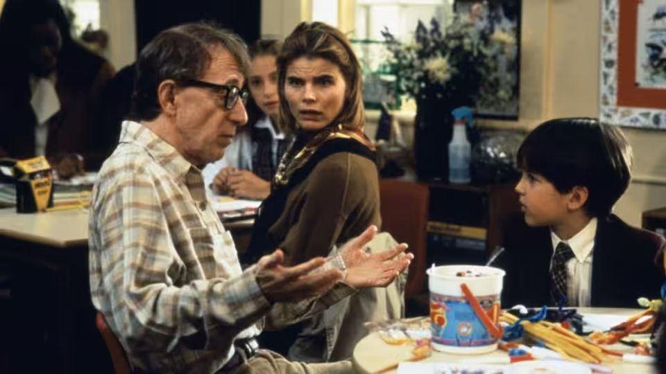 Harry (Woody Allen) gestures across a restaurant table as a woman and boy watch