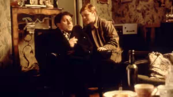 Francie Brady (Eamonn Owens) leans beside his seated father at home