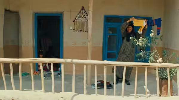 A woman hangs laundry from a line on a village balcony