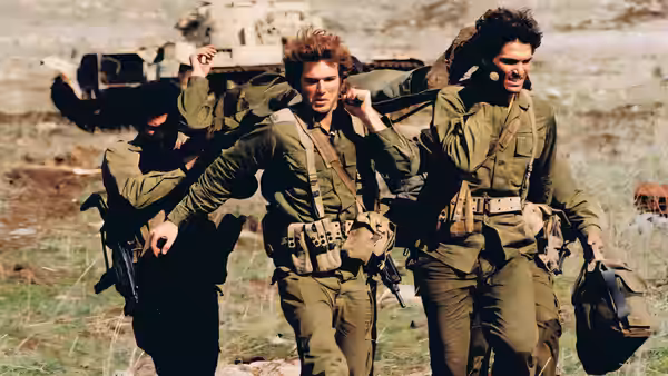 Soldiers in uniform carry a wounded man across open ground