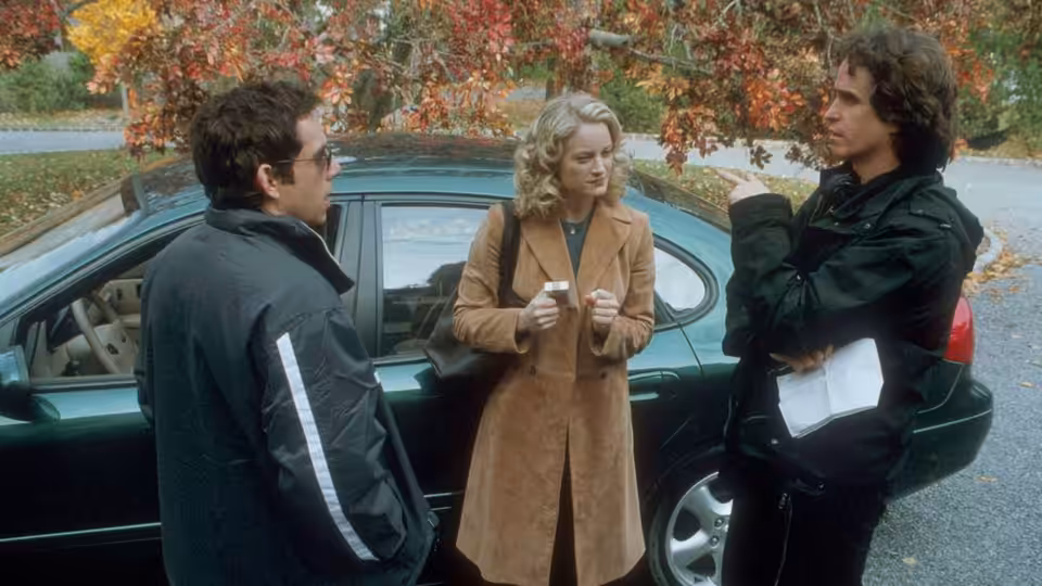 Greg, Pam, and Kevin stand beside a car beneath autumn trees