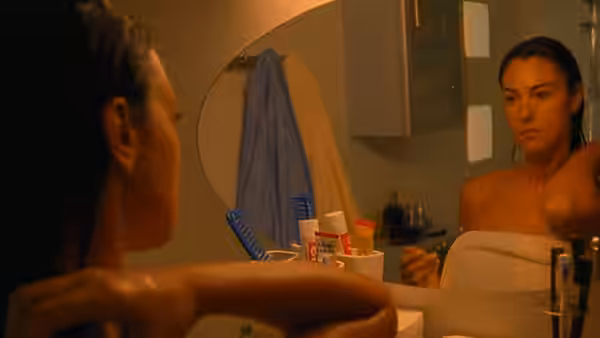 Alex (Monica Bellucci) looks into a bathroom mirror, wrapped in a towel