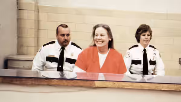Aileen Wuornos (Self) smiling in court between two uniformed officers