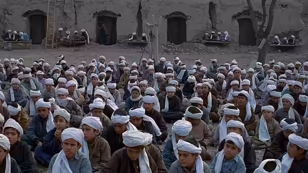 Rows of boys sit in a courtyard outside a weathered building