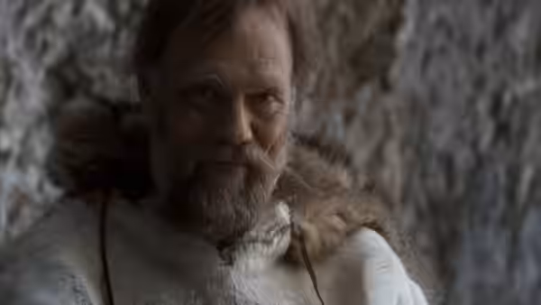 A bearded man in fur clothing faces the camera
