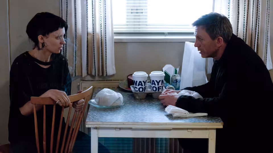 Lisbeth Salander (Rooney Mara) and Mikael Blomkvist (Daniel Craig) talk across a small table