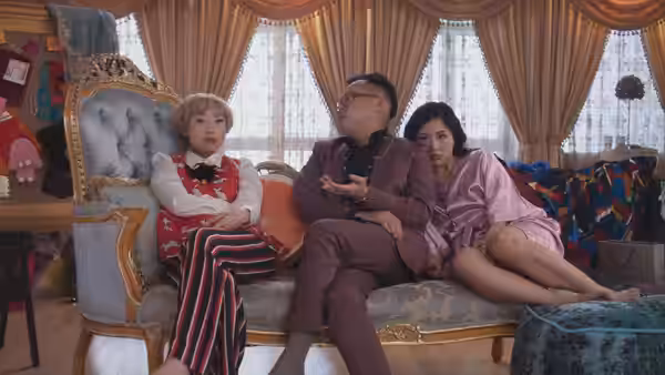 Peik Lin (Awkwafina) lounges with her parents on an ornate living room sofa