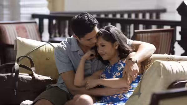Nick Young (Henry Golding) embraces Rachel Chu (Constance Wu) on a cushioned patio sofa