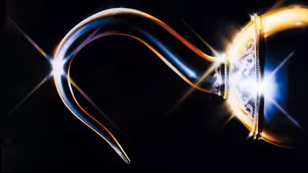 An ornate golden hook curves and gleams against a black background