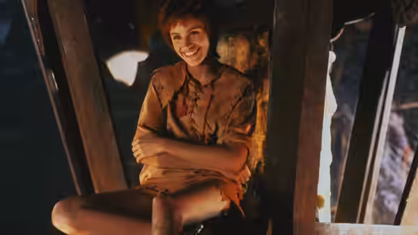 Tinkerbell (Julia Roberts) sits smiling with arms crossed inside a wooden structure