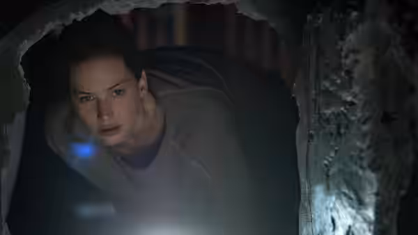 Mother (Jennifer Lawrence) peers through a hole in the damaged wall