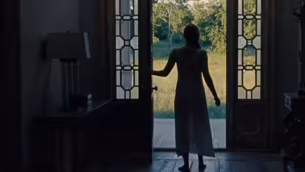 Mother (Jennifer Lawrence) stands in the open doorway, facing the garden