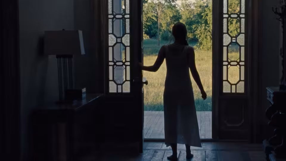 Mother (Jennifer Lawrence) stands in the open doorway, facing the garden