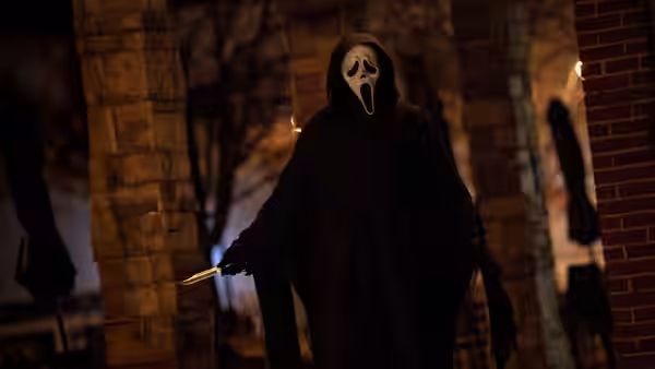 A masked figure holds a knife while standing outside at night