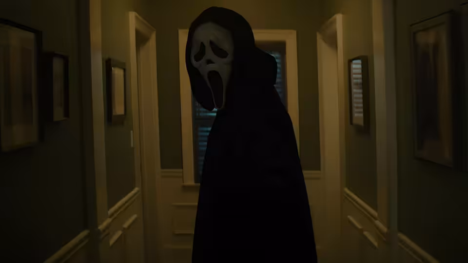 A masked figure in a black robe stands in a dimly lit hallway