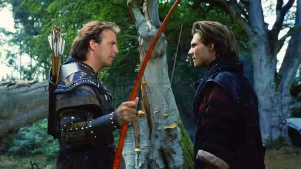 Robin Hood (Kevin Costner) facing a man with a bow in the forest