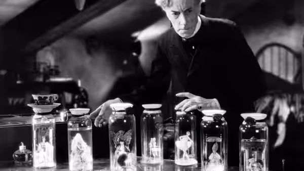 Doctor Pretorius (Ernest Thesiger) studies miniature figures in specimen jars