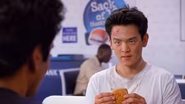 Harold (John Cho) holds a burger inside a White Castle restaurant
