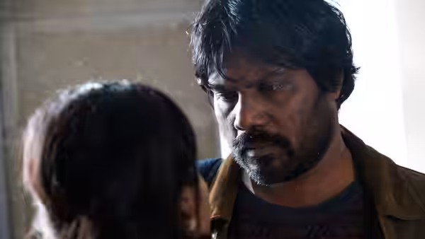 Dheepan (Antonythasan Jesuthasan) looks intently at a child standing before him indoors