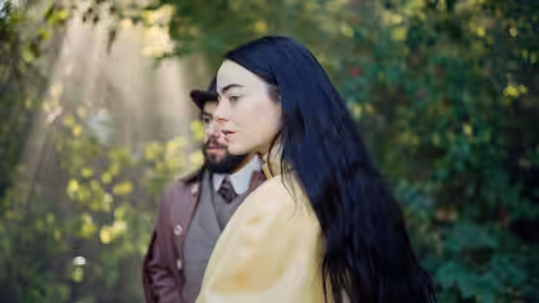 woman with long dark hair standing in forest beside bearded man